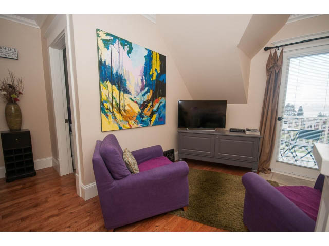 Bright living room with purple furniture, hardwood floors, and a city view. - 266 W 6th St, North Vancouver