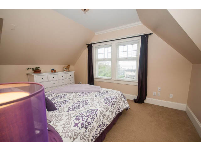 Bright bedroom with purple and white bedding, hardwood floors, and a window view. - 266 W 6th St, North Vancouver