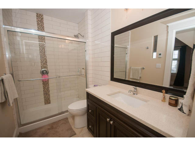 Furnished bathroom with white subway tile, glass shower, and dark wood vanity. - 266 W 6th St, North Vancouver