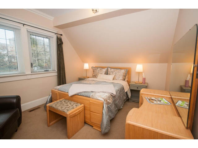 Furnished bedroom with wooden furniture, city view, and modern decor. - 266 W 6th St, North Vancouver