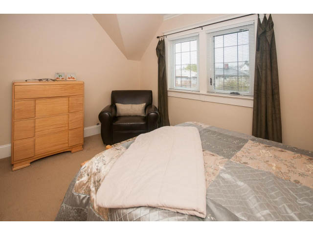 Furnished bedroom with a queen bed, nightstand, and city view through the window. - 266 W 6th St, North Vancouver