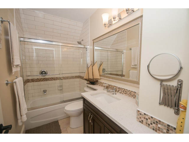 Furnished bathroom with white subway tile, dark wood cabinets, and a modern sink. - 266 W 6th St, North Vancouver