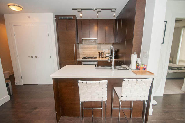 Bright kitchen with white countertops, dark wood cabinets, and hardwood floors. - 1003 - 535 Smithe St, Vancouver Downtown
