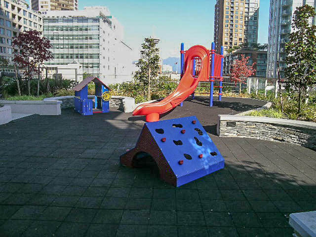Playful rooftop playground with colorful slides and climbing structures, surrounded by urban buildings. - 1003 - 535 Smithe St, Vancouver Downtown