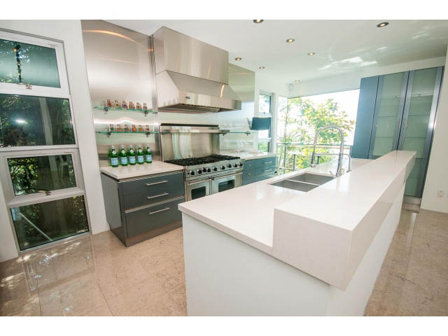 Bright kitchen with white countertops and stainless steel appliances, featuring a city view. - 5517 Ocean Place, West Vancouver