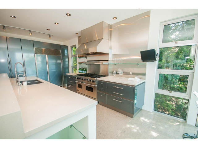 Bright kitchen with sleek white countertops and large windows offering a city view. - 5517 Ocean Place, West Vancouver
