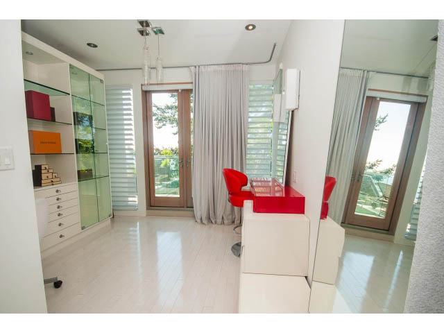 Spacious living room with hardwood floors, large windows, and a red accent chair. - 5517 Ocean Place, West Vancouver