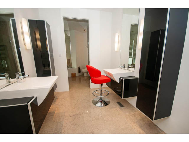 Modern bathroom with white vanity, red chairs, and large mirrors. - 5517 Ocean Place, West Vancouver