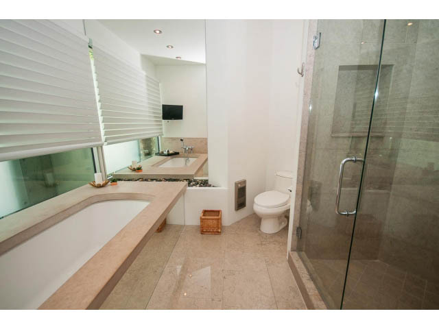 Modern bathroom with large glass shower, sleek countertop, and neutral tones. - 5517 Ocean Place, West Vancouver