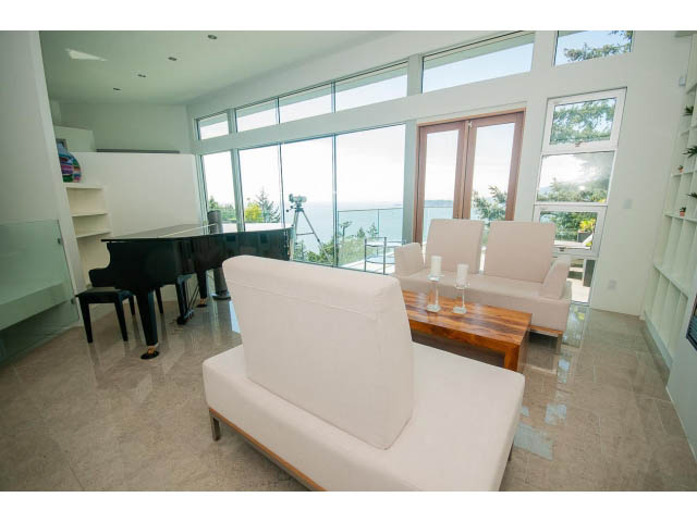 Bright living room with large windows, ocean view, and modern furniture. - 5517 Ocean Place, West Vancouver