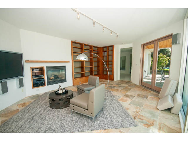 Open-concept living room with modern furniture, stone countertops, and sliding glass doors leading to a patio. - 5517 Ocean Place, West Vancouver