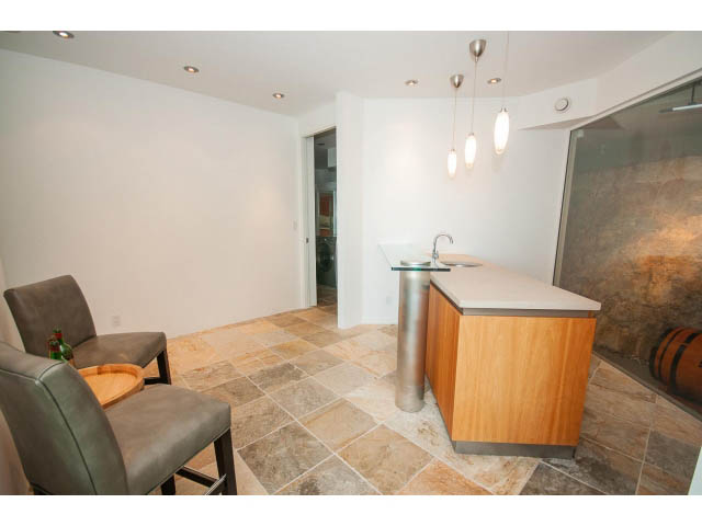 Modern kitchen with granite countertops and wooden cabinets. - 5517 Ocean Place, West Vancouver