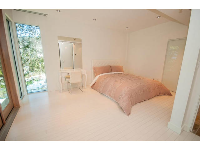 Spacious bedroom with white walls, wooden floors, and a large window offering a view. - 5517 Ocean Place, West Vancouver