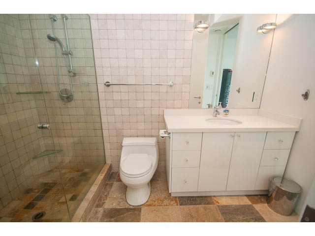 Bright bathroom with white countertops and tiled walls, featuring a shower and toilet. - 5517 Ocean Place, West Vancouver