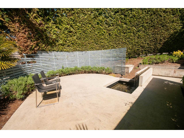 Furnished patio with modern seating and water feature, surrounded by greenery. - 5517 Ocean Place, West Vancouver