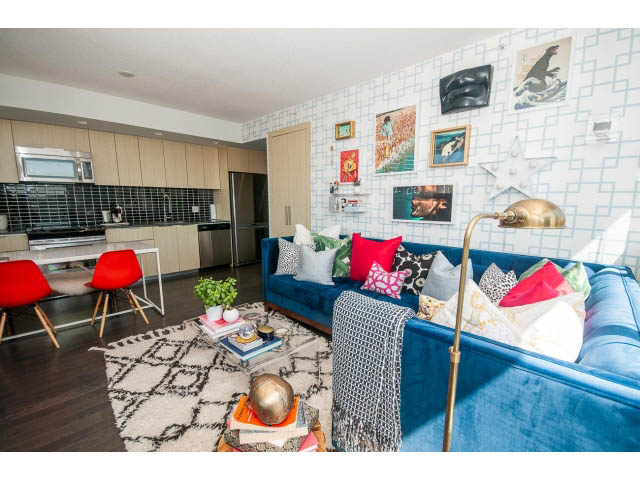 Furnished living room with blue velvet sofa, patterned wall, and hardwood floors. - 2606 - 1325 Rolston Street, Vancouver Downtown