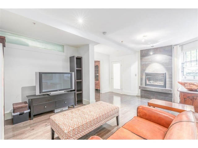 Bright living room with hardwood floors, orange couch, and fireplace. - 1 - 2888 Birch Street, Vancouver West Side