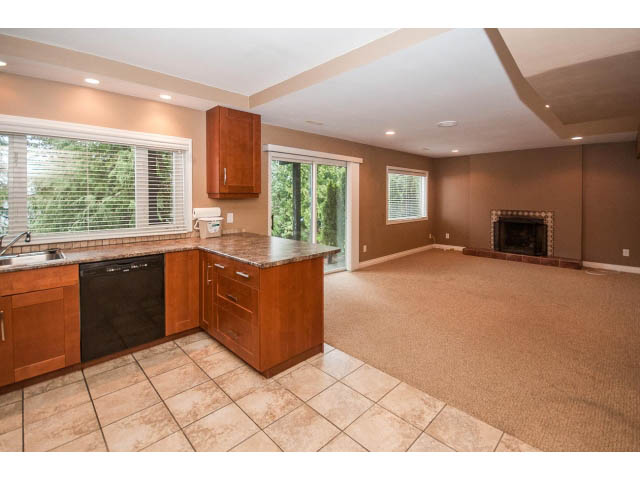 Bright kitchen with granite countertops and tiled floor, leading to a cozy living area with fireplace and sliding glass...