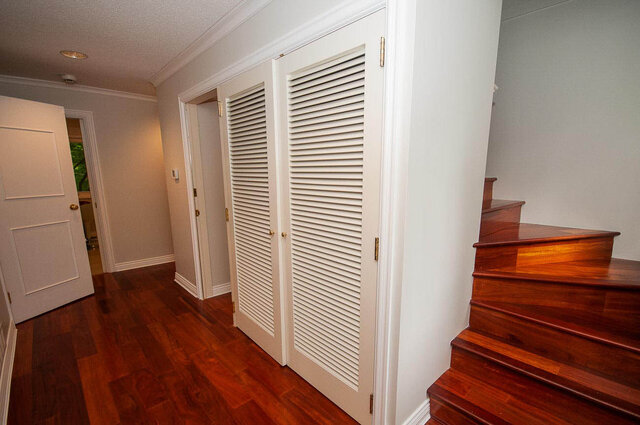 Hallway with rich hardwood floors and a polished wooden staircase leading upstairs. - 5367 Esperanza Drive, North Vancouver