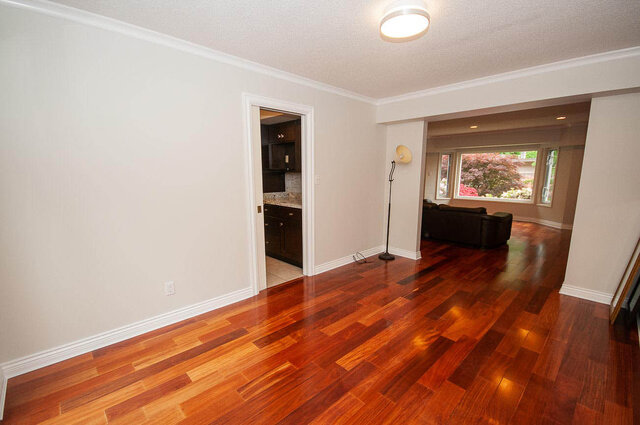 Spacious living area with rich hardwood floors and views of lush gardens through large windows. - 5367 Esperanza Drive, North Vancouver