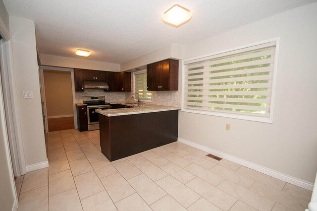 Bright kitchen with granite countertops and dark wooden cabinetry. - 5367 Esperanza Drive, North Vancouver