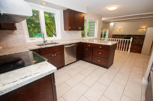 Bright kitchen with granite countertops and dark wood cabinets overlooking lush greenery. - 5367 Esperanza Drive, North Vancouver