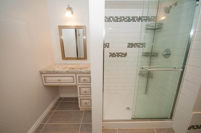 Bathroom with granite vanity countertop and glass shower featuring mosaic tile accents. - 5367 Esperanza Drive, North Vancouver