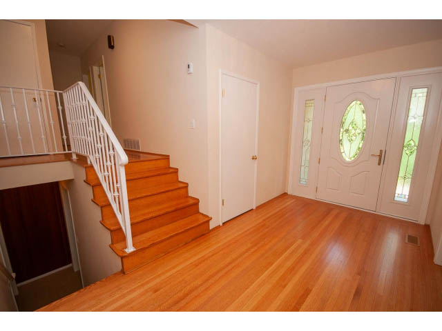 Bright entryway with hardwood floors and white railings leading to stairs. - 315 Stevens Dr, West Vancouver