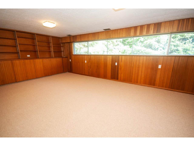 Spacious living room with wood-paneled walls and large windows. - 315 Stevens Dr, West Vancouver