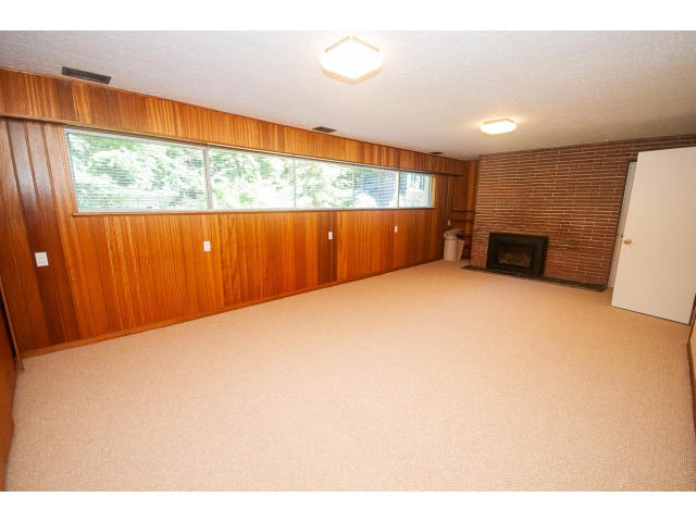 Bright living room with wood-paneled walls and large windows, showcasing a city view. - 315 Stevens Dr, West Vancouver