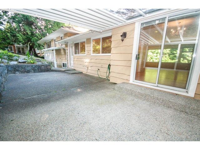 Bright patio with wooden deck and glass doors leading inside. - 315 Stevens Dr, West Vancouver