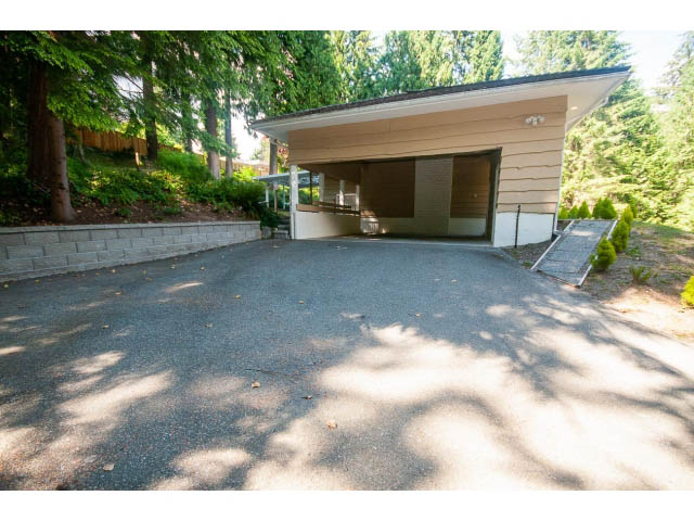 Spacious garage with large doors and concrete driveway, surrounded by trees. - 315 Stevens Dr, West Vancouver