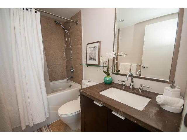 Furnished bathroom with dual sinks, marble countertops, and a shower. - 2702 - 918 Cooperage Way, Vancouver Downtown