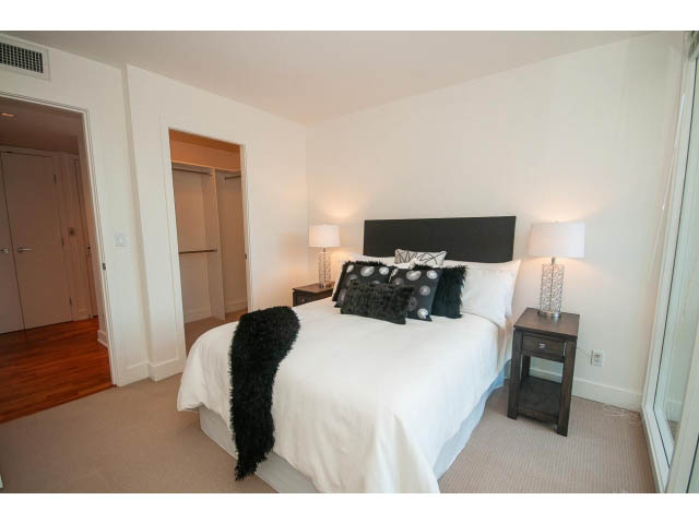 Bright bedroom with white walls, black headboard, and fluffy throw pillows. - 703 - 1863 Alberni Street, Vancouver Downtown