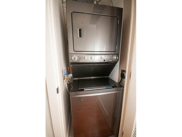 Bright laundry room with stacked washer and dryer, hardwood floors. - 703 - 1863 Alberni Street, Vancouver Downtown