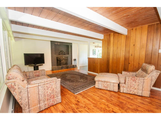 Spacious living room with hardwood floors, patterned couches, and a fireplace. - 640 East Queens Rd, North Vancouver