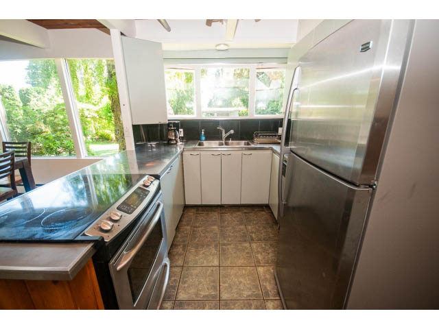 Bright kitchen with stainless steel appliances and granite countertops, open to a sunny outdoor space. - 640 East Queens Rd, North Vancouver