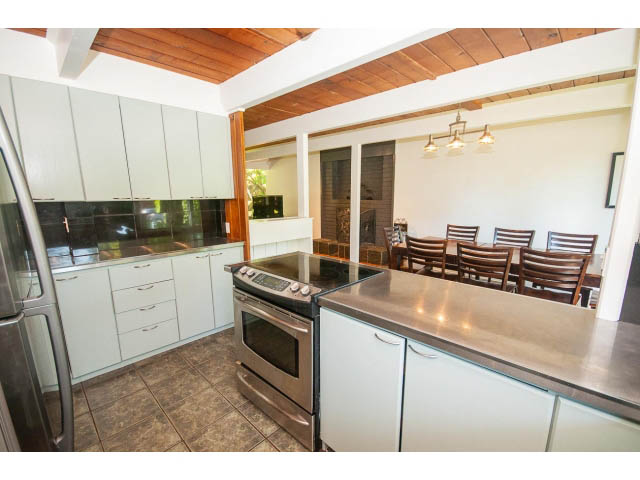 Bright kitchen with stainless steel countertops and white cabinets, featuring a modern design and a cozy dining area.