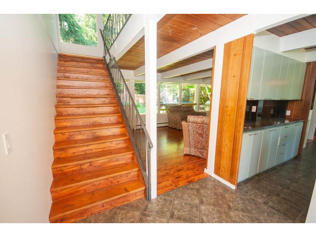 Bright kitchen with wooden stairs leading to second floor, hardwood floors, and a view of the backyard. - 640 East Queens Rd, North Vancouver