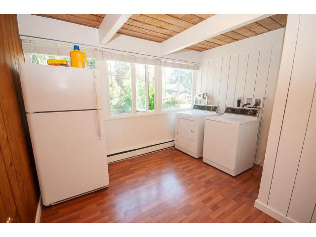Bright kitchen with white appliances, hardwood floors, and a view of greenery outside. - 640 East Queens Rd, North Vancouver