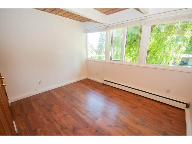 Bright living room with hardwood floors and large windows, allowing natural light to flood in. - 640 East Queens Rd, North Vancouver