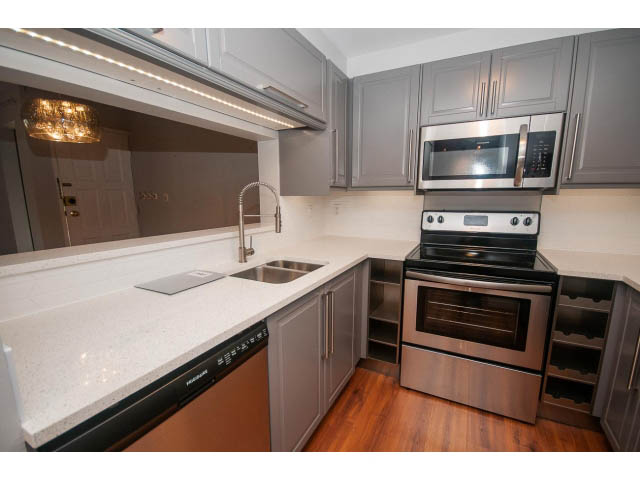 Bright kitchen with white countertops, stainless steel appliances, and hardwood floors. - 123 - 1363 Clyde Avenue, West Vancouver