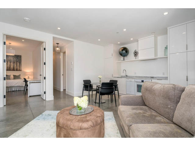 Furnished living room with modern decor, open kitchen, and concrete floors. - Address WITHHELD, West Vancouver