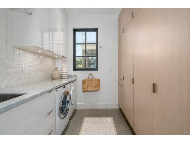 Bright laundry room with white cabinets, marble countertops, and a city view. - Address WITHHELD, West Vancouver