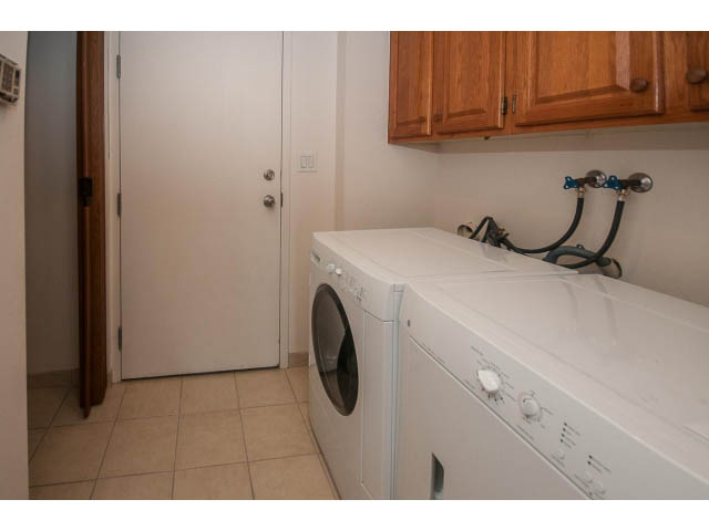 Bright laundry room with white appliances and wooden cabinets. - 2150 Argyle Ave., West Vancouver