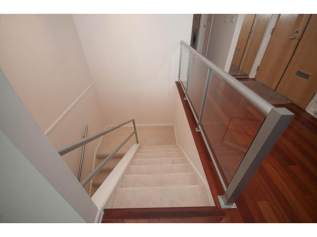 Staircase leading to upper floor with glass railings and hardwood flooring. - 2150 Argyle Ave., West Vancouver