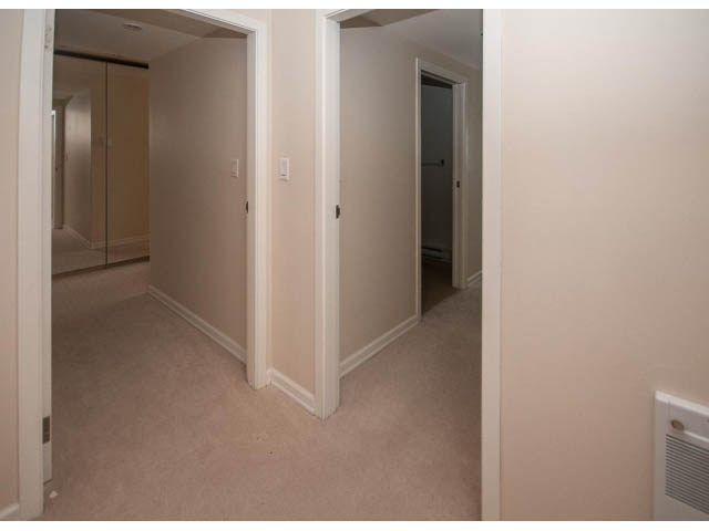 Bright hallway leading to a bedroom with carpeted floors and a door to another room. - 2150 Argyle Ave., West Vancouver