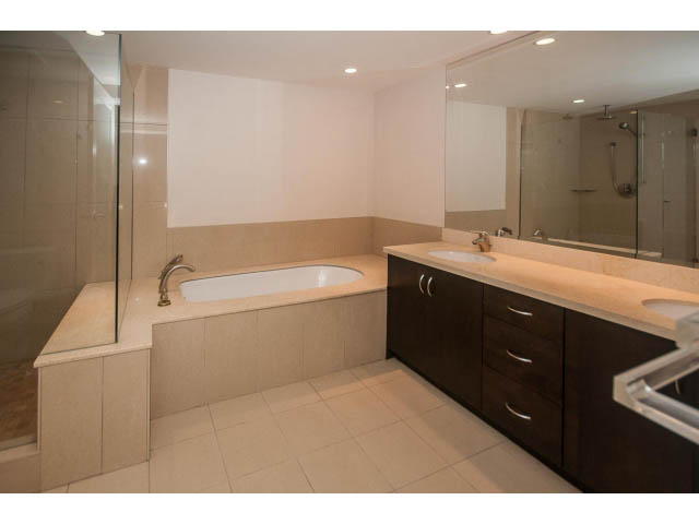 Modern bathroom with dual sinks, large mirror, and glass shower. - 2150 Argyle Ave., West Vancouver