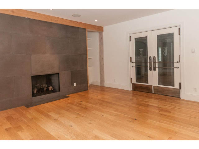 Spacious living room with hardwood floors, modern fireplace, and French doors leading to a patio. - 5630 Angus Dr., Vancouver West Side