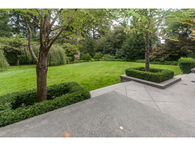 Furnished living room with stone fireplace and lush garden view. - 5630 Angus Dr., Vancouver West Side